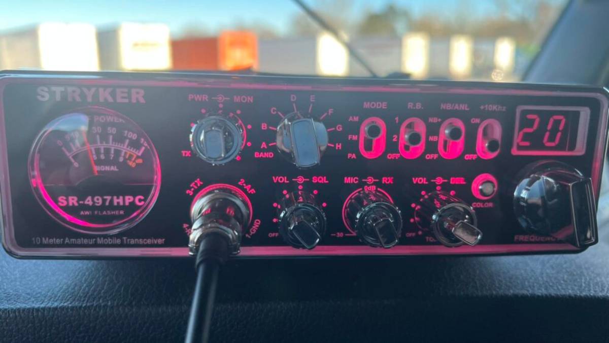 Close-up of a Stryker SR-497HPC 10-meter amateur mobile transceiver, featuring various dials, a power meter, and digital frequency display.
