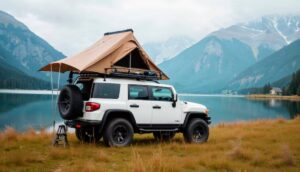 A white SUV with a rooftop tent parked by a serene lake, surrounded by mountains and lush greenery. Perfect for outdoor adventure.