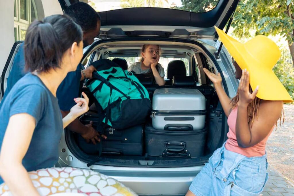A group of friends are loading luggage into a car trunk, with colorful bags and a bright yellow hat enhancing the vibrant atmosphere.