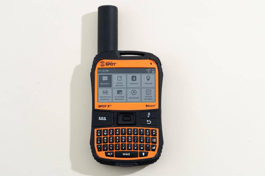 Black and orange SPOT X satellite messenger with a screen displaying various features and a keypad for messaging and navigation.