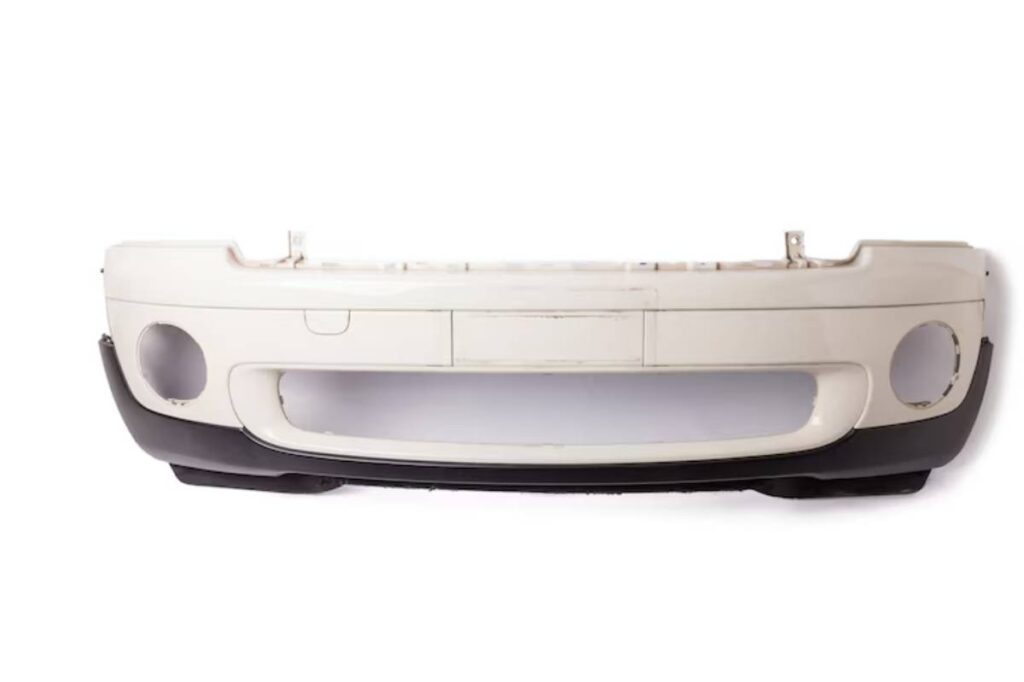 White car front bumper with a black lower edge, featuring cutouts for headlights and a central grille space, displayed on a white background.